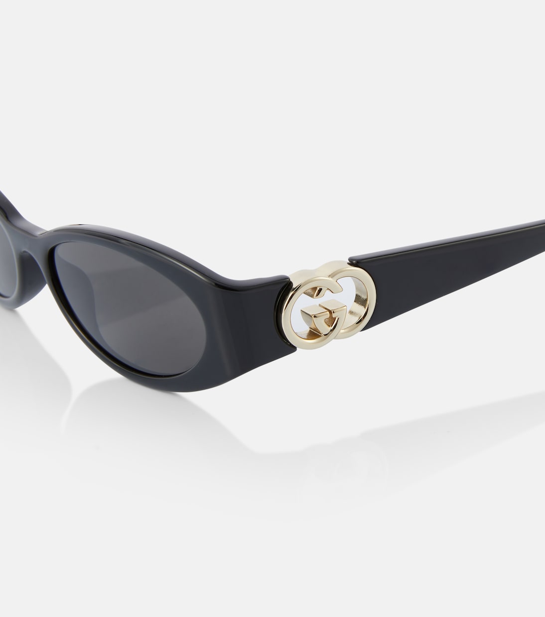 Occhiali da sole GUCCI con design ovale e logo intrecciato, stile giovane e moderno.