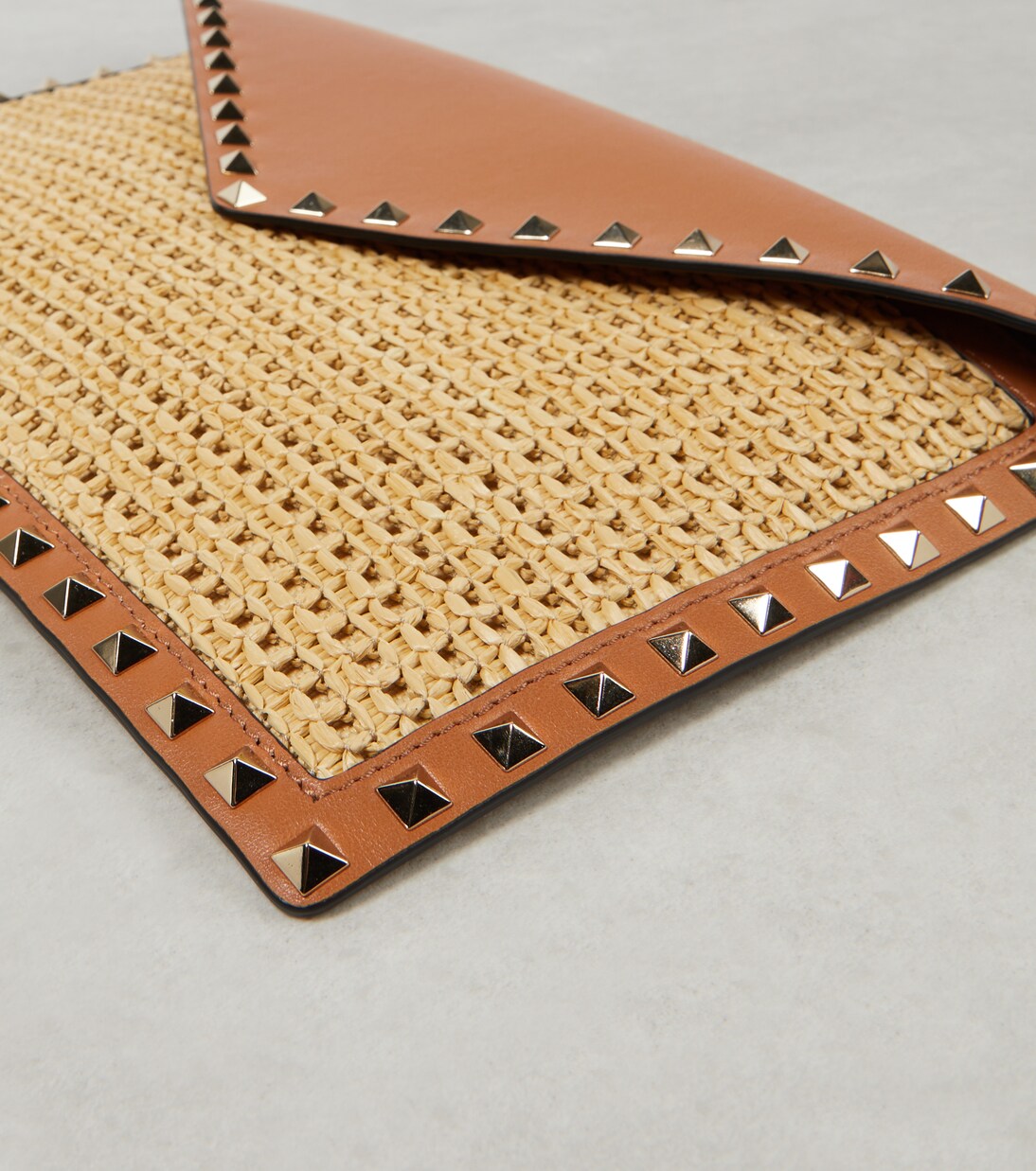 Rockstud Large leather-trimmed raffia clutch | Valentino Garavani