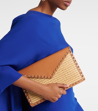 Rockstud Large leather-trimmed raffia clutch | Valentino Garavani